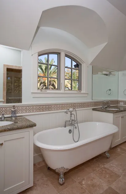 Bath in a Burlingame residence with a freestanding tub, a stone counter, and an arched window.