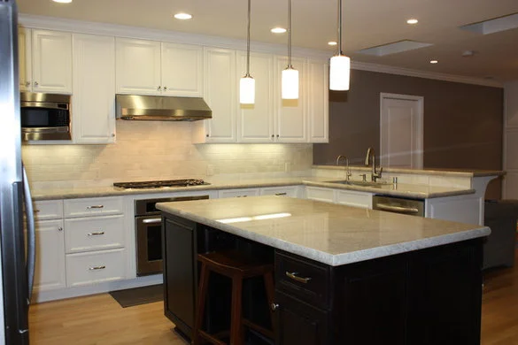 Kitchen with a dark island, light stone counters, and a subway-tile backsplash.